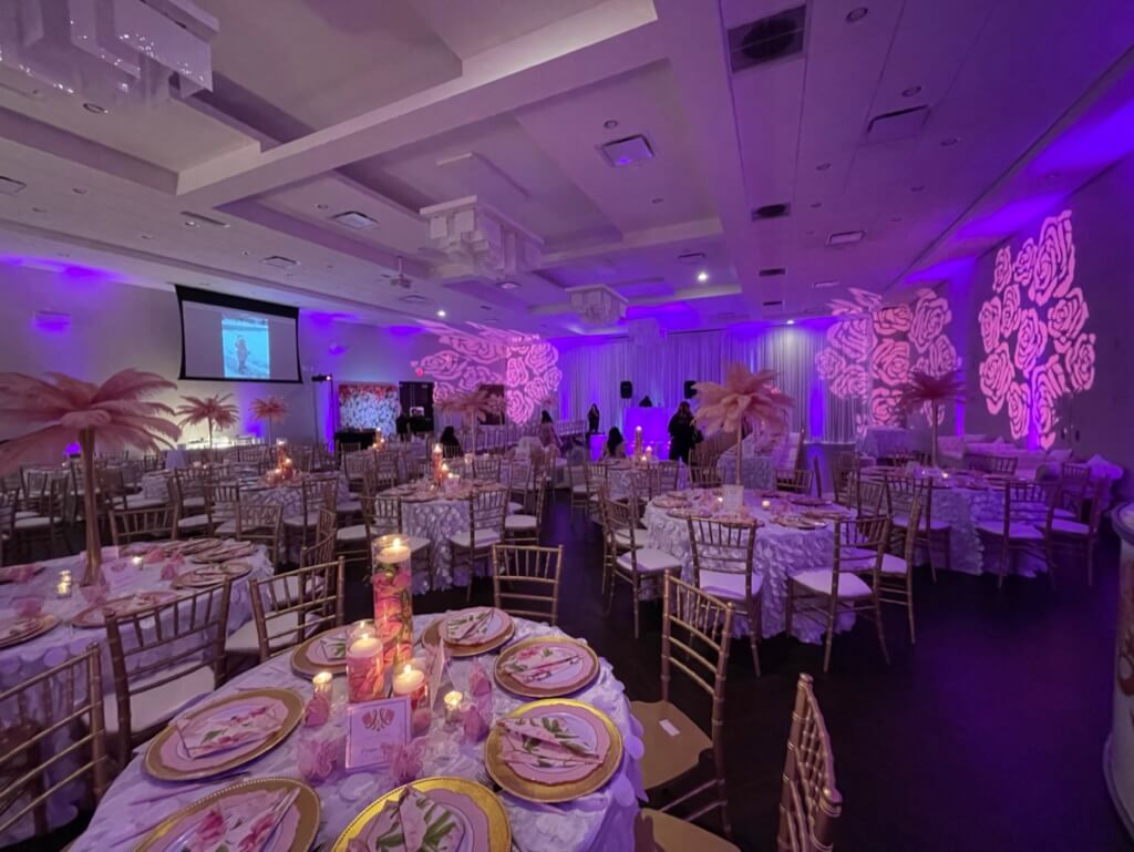 Elegantly set tables and ambient lighting in a decorated event hall with guests.
