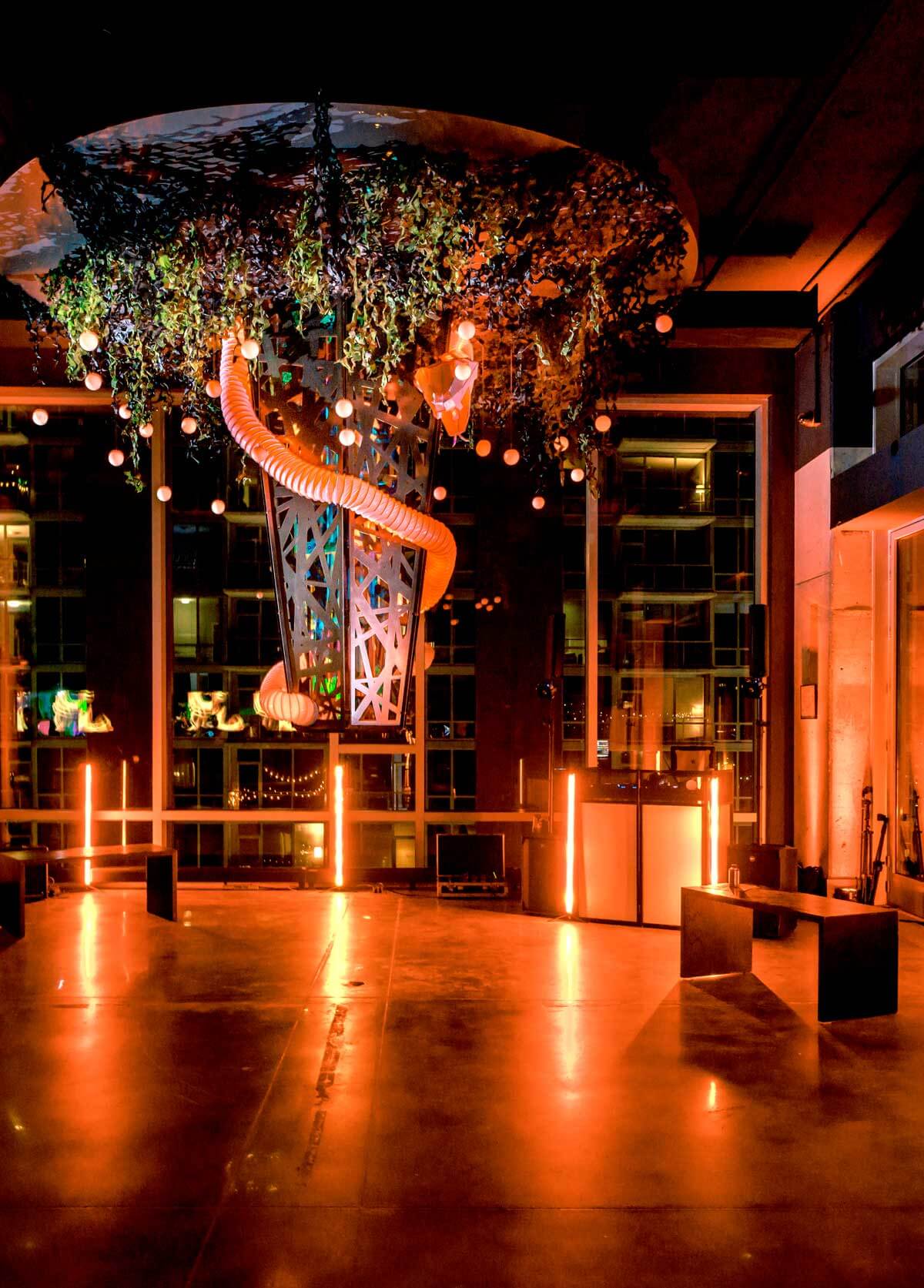 Elegant modern interior of a dimly lit space with an intricate hanging sculpture and warm ambient lighting.
