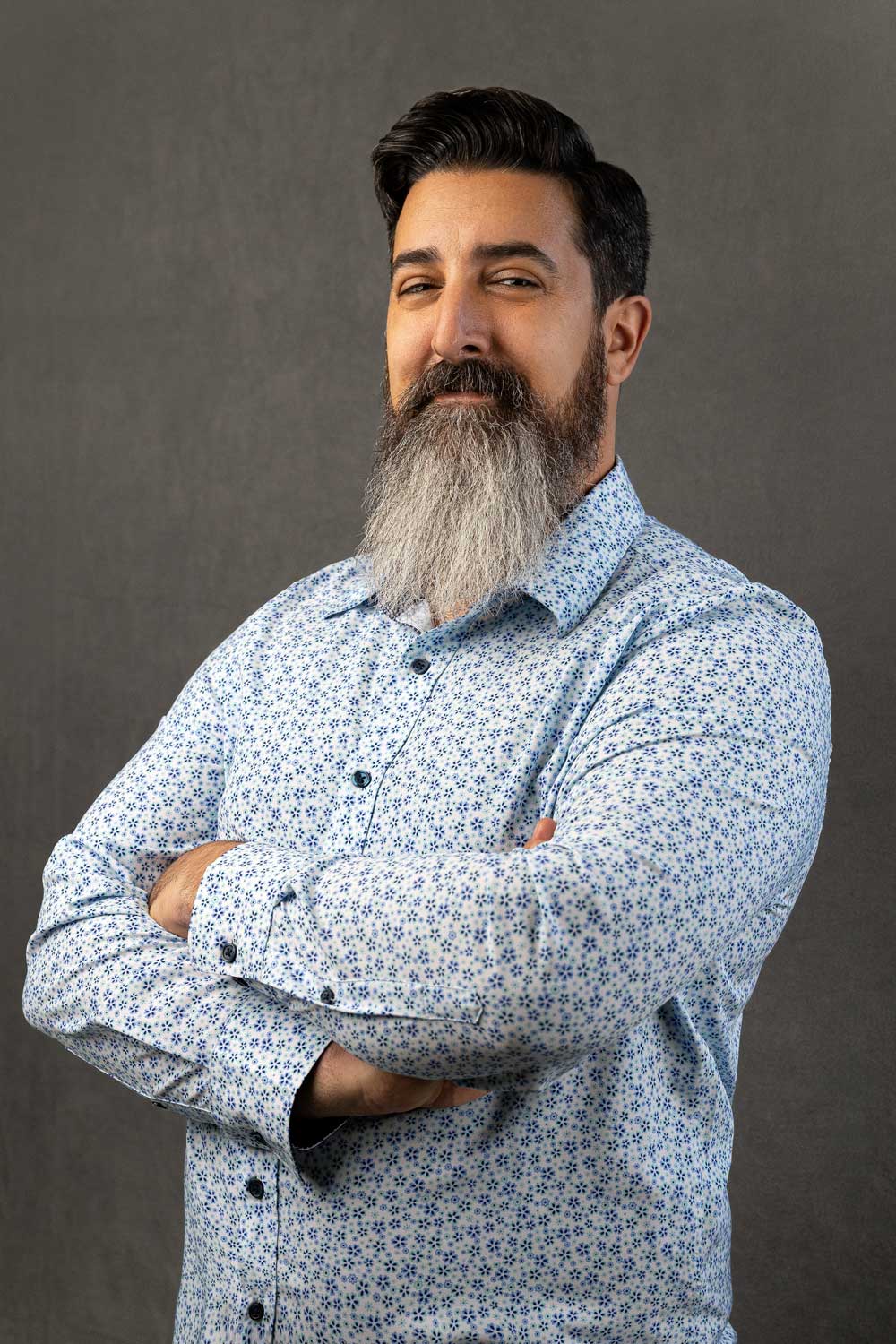 Yoni-Yemini-CEO A confident man with a full beard smiling at the camera with his arms crossed.