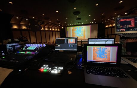 Control room view with multiple screens and lighting equipment during a live production.