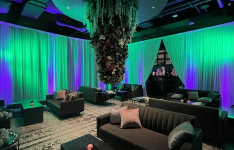 A modern lounge with ambient lighting, comfortable seating, and an overhead floral installation.