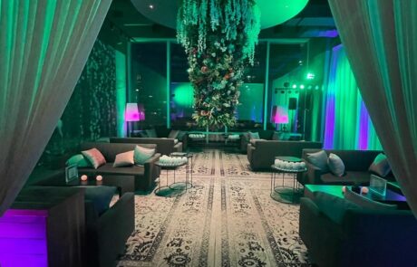 An upscale lounge with ambient lighting, plush seating, and a dramatic hanging plant installation.
