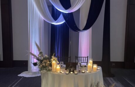 Elegantly decorated sweetheart table with draped fabric and ambient candlelight for a wedding reception.