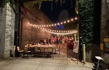 Evening gathering at an outdoor venue with string lights and seated guests.