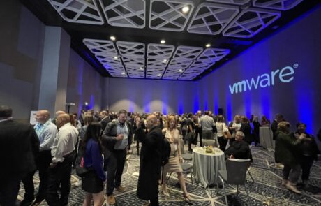 Networking event at a conference with attendees mingling near a vmware banner.