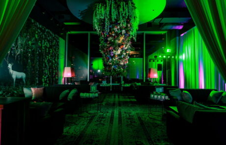 A vibrant lounge area with neon lighting and a floral centerpiece.