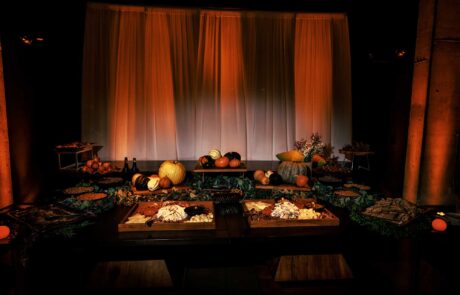 An elegant autumnal banquet setup with a variety of squash, candles, and mood lighting.