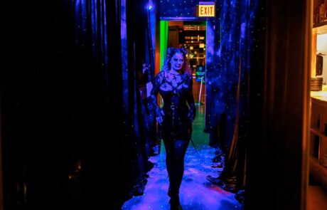 A person walking through a vividly lit corridor with blue lights and star-like projections on the floor.