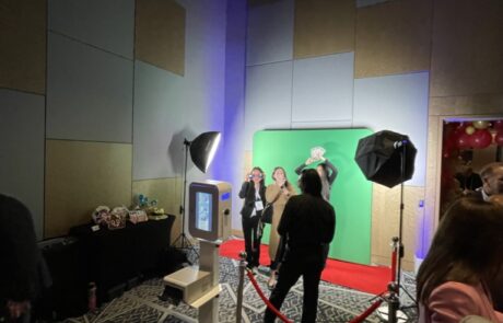 Photobooth setup with green screen and lighting equipment at an indoor event.