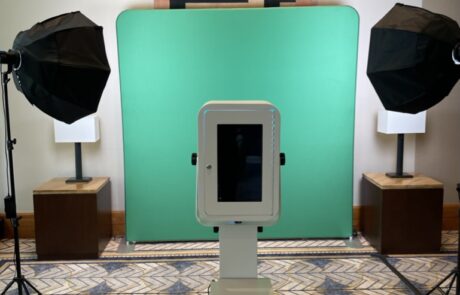 A photo booth setup with a green screen background and professional lighting equipment.