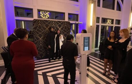 Guests in formal attire at an indoor event with a check-in kiosk in the foreground.