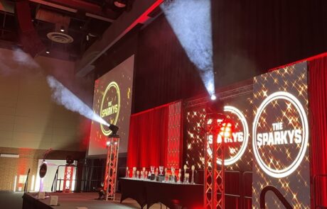 An awards ceremony stage with red lighting, smoke effects, and a banner titled "the sparkys.