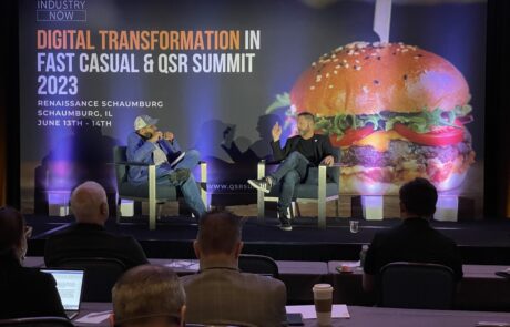 Two panelists engage in discussion at the digital transformation in fast casual & qsr summit 2023, with attendees listening in the audience.