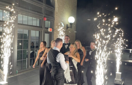 Group of elegantly dressed people enjoying a celebration with sparklers at night.